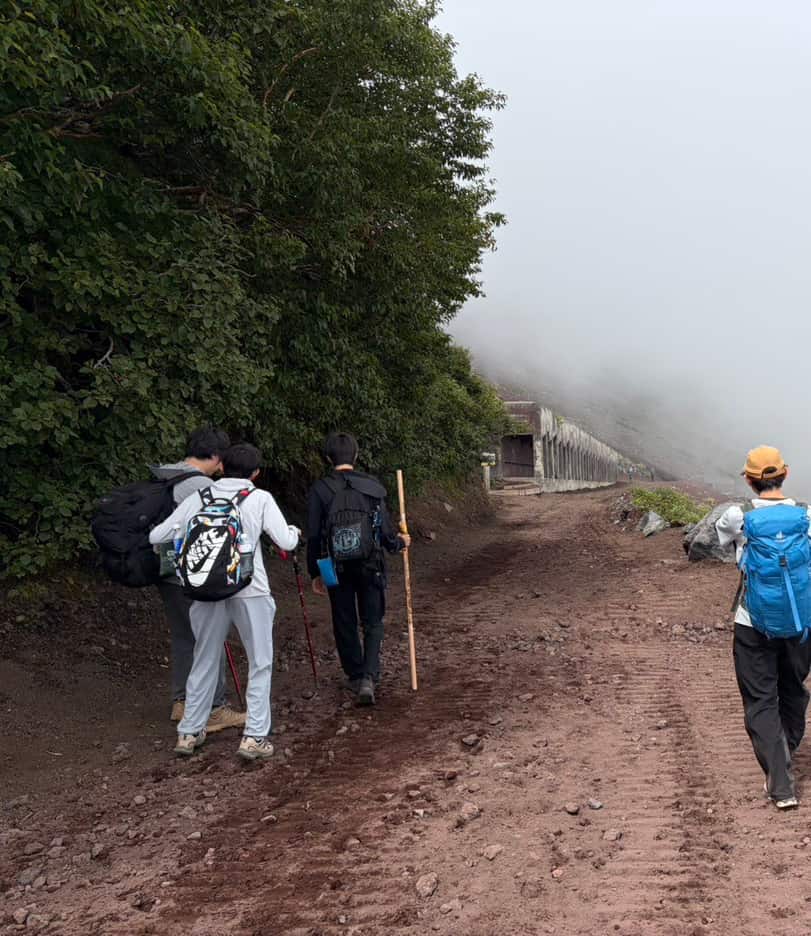 霧のかかった下山道を、ザックを背負って下りていく後ろ姿